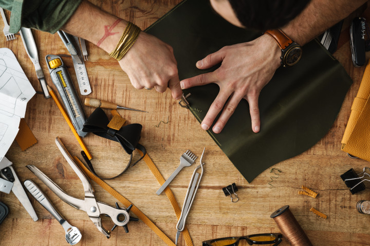 Bovenaanzicht van een hobbyist die leer bewerkt met gereedschap voor leerbewerking